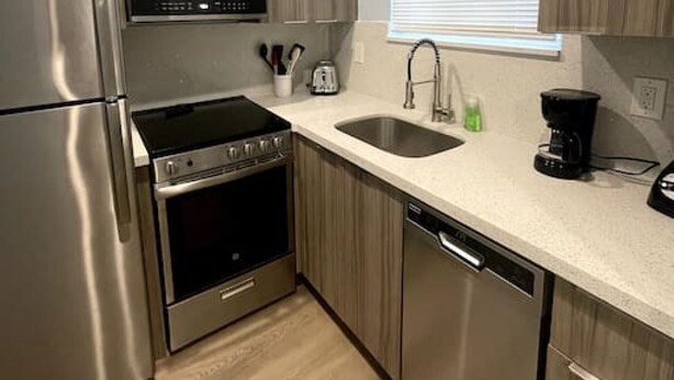 A modern kitchen with stainless steel appliances, a dishwasher, and wooden cabinetry.