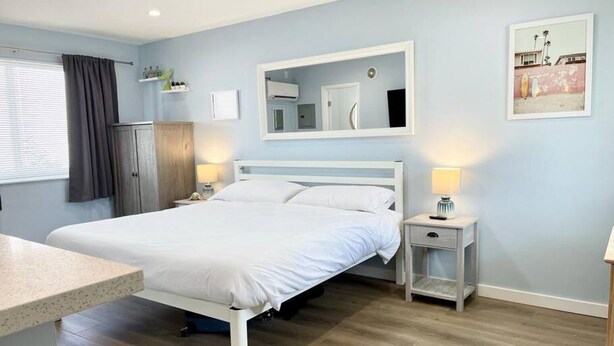 Ein Schlafzimmer mit Bett, Nachttischen, einem Kleiderschrank, einem Spiegel und einem Bild an der Wand.