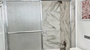 Ein Badezimmer mit Duschkabine, Toilette und Wänden im Marmoroptik.
