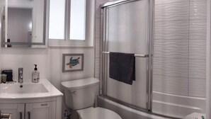 A modern bathroom with a white sink, toilet, and shower enclosure. - Charming DBL w/pool& parking 15 min to FLL & Beach (Hollywood)