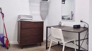 A compact bedroom with a wooden dresser, a white chair, a desk with a computer, and a mirror. - Charming DBL w/pool& parking 15 min to FLL & Beach (Hollywood)