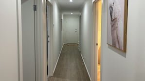 Passadís estret amb parets blanques i terres de fusta, que condueix a una porta al final.