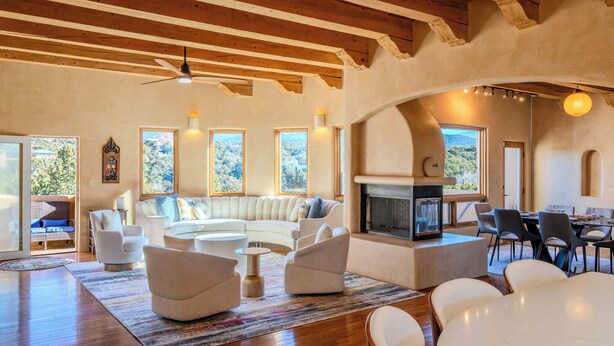 A spacious living room with a fireplace, wooden beams, and large windows offering a view of the outdoors. - Amazing views, Stunning Sunny Interior (Santa Fe)