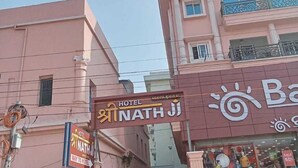 Een roze gebouw met een bordje Hotel Nath Ji.