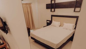Een moderne hotelkamer met een groot bed, een plafondventilator en een minimalistische inrichting.