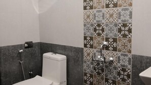 A small bathroom with a toilet, a shower, and a sink. - Parth Guesthouse (Morjim)