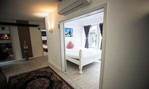 Een slaapkamer met een bed, nachtkastje, raam met gordijnen en uitzicht.