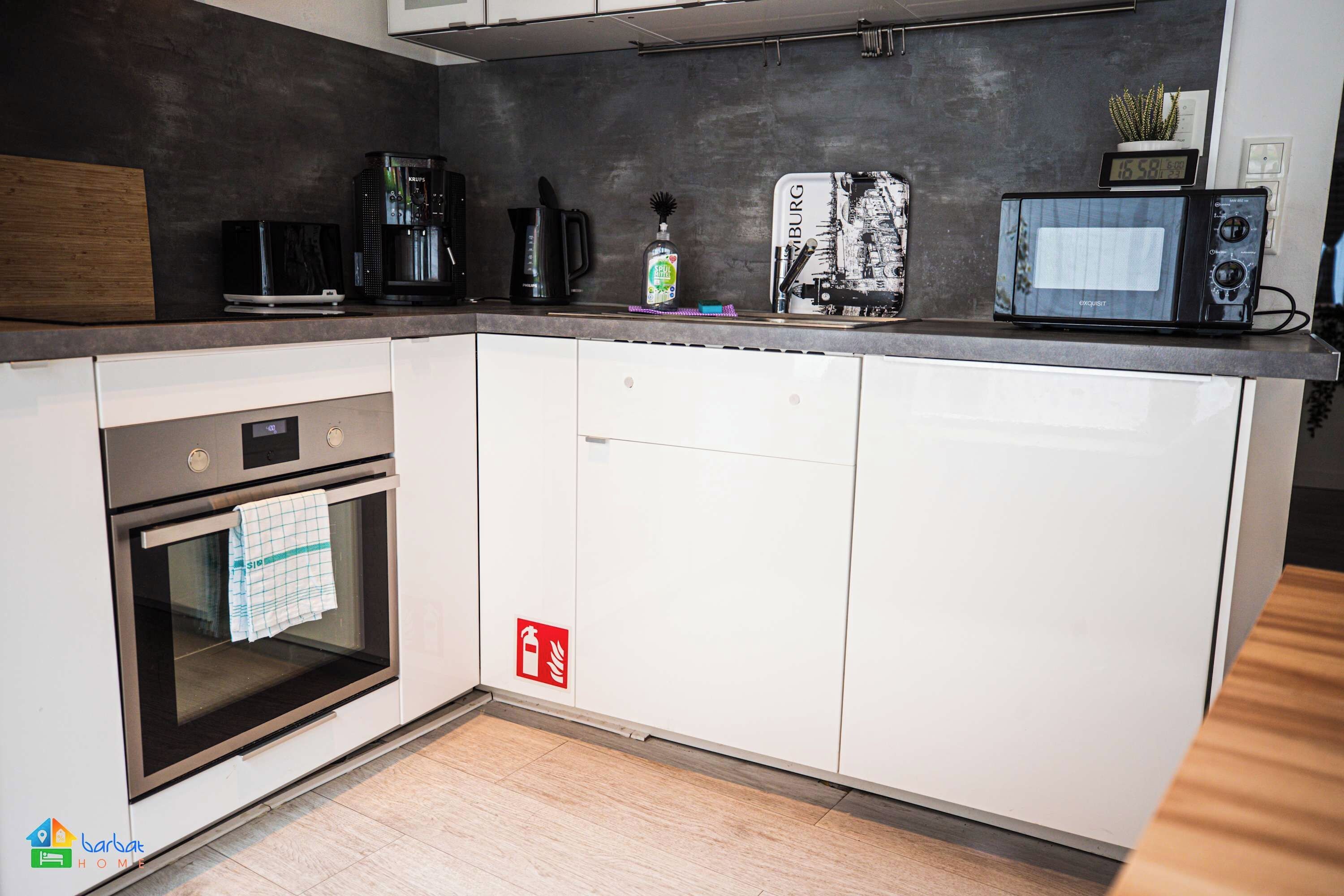 Una cocina moderna con horno empotrado, microondas y cafetera.