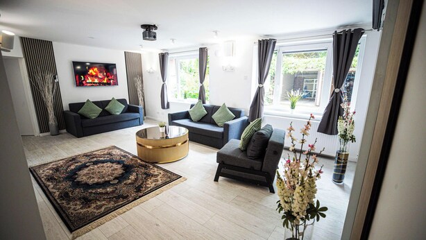 A modern living room with two sofas, a coffee table, a large rug, and a fireplace.