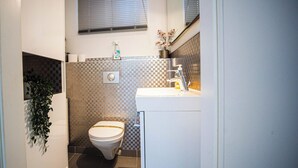A bathroom with a toilet, sink, and a plant.