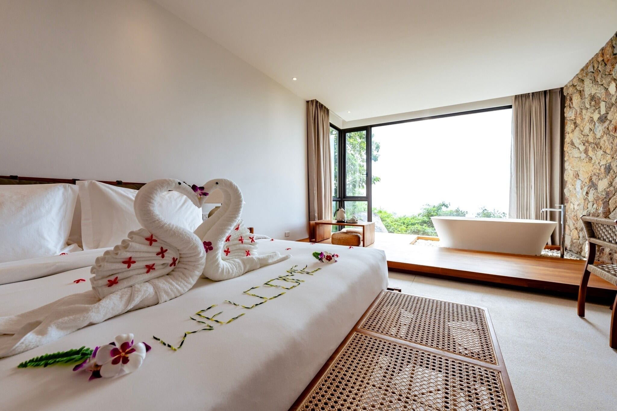Habitación de hotel con cama, bañera, una silla y vistas a zonas verdes.