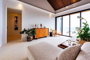A spacious living area with a large window, a wooden cabinet, and a comfortable seating area. - Anzhu Seamate Villa Samui (Koh Samui)