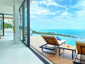 Un espace de détente extérieur moderne, avec vue sur l’océan et une piscine.