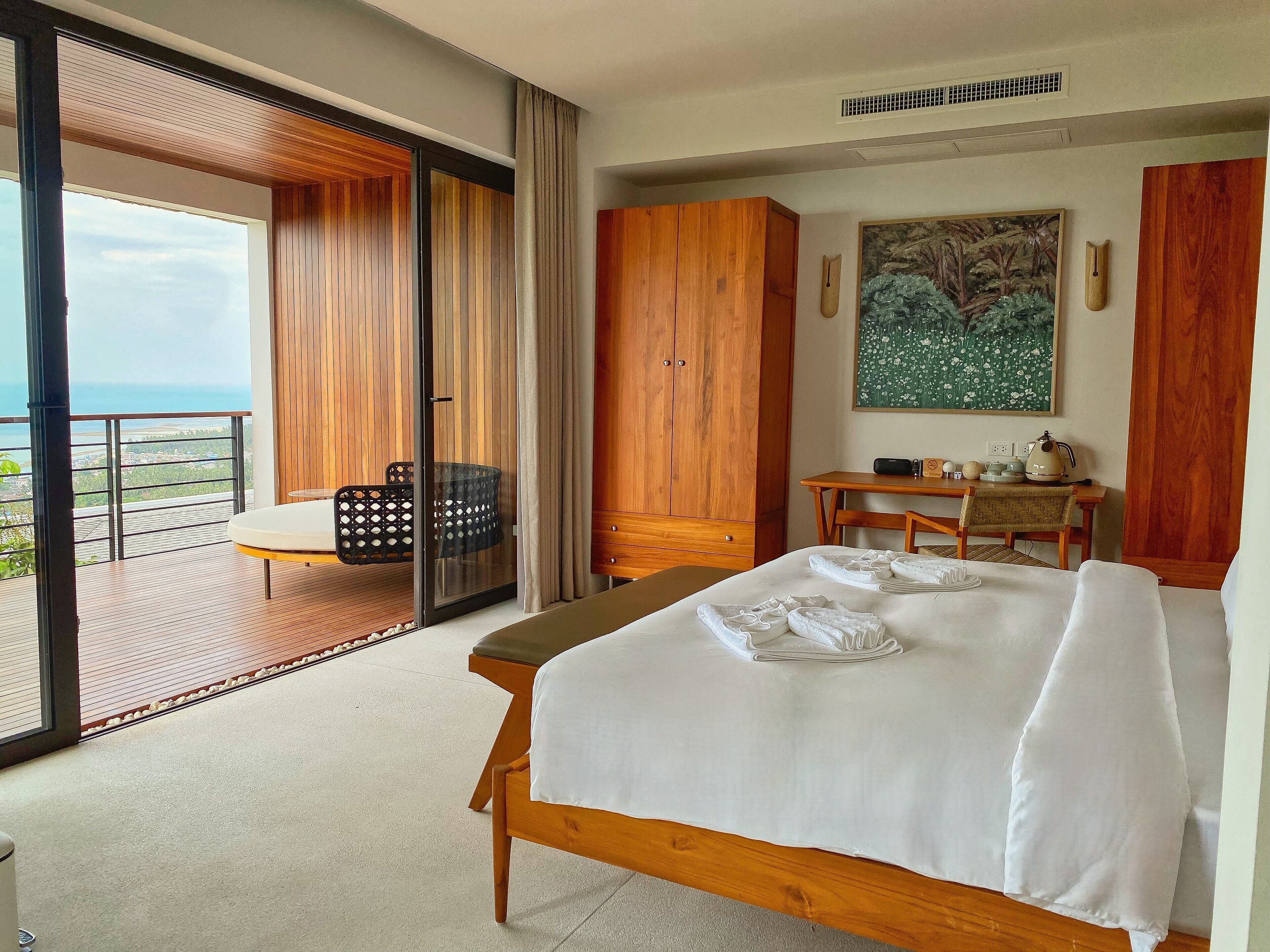 Ein Hotelzimmer mit Bett, Schreibtisch, Stuhl und Blick auf das Meer.
