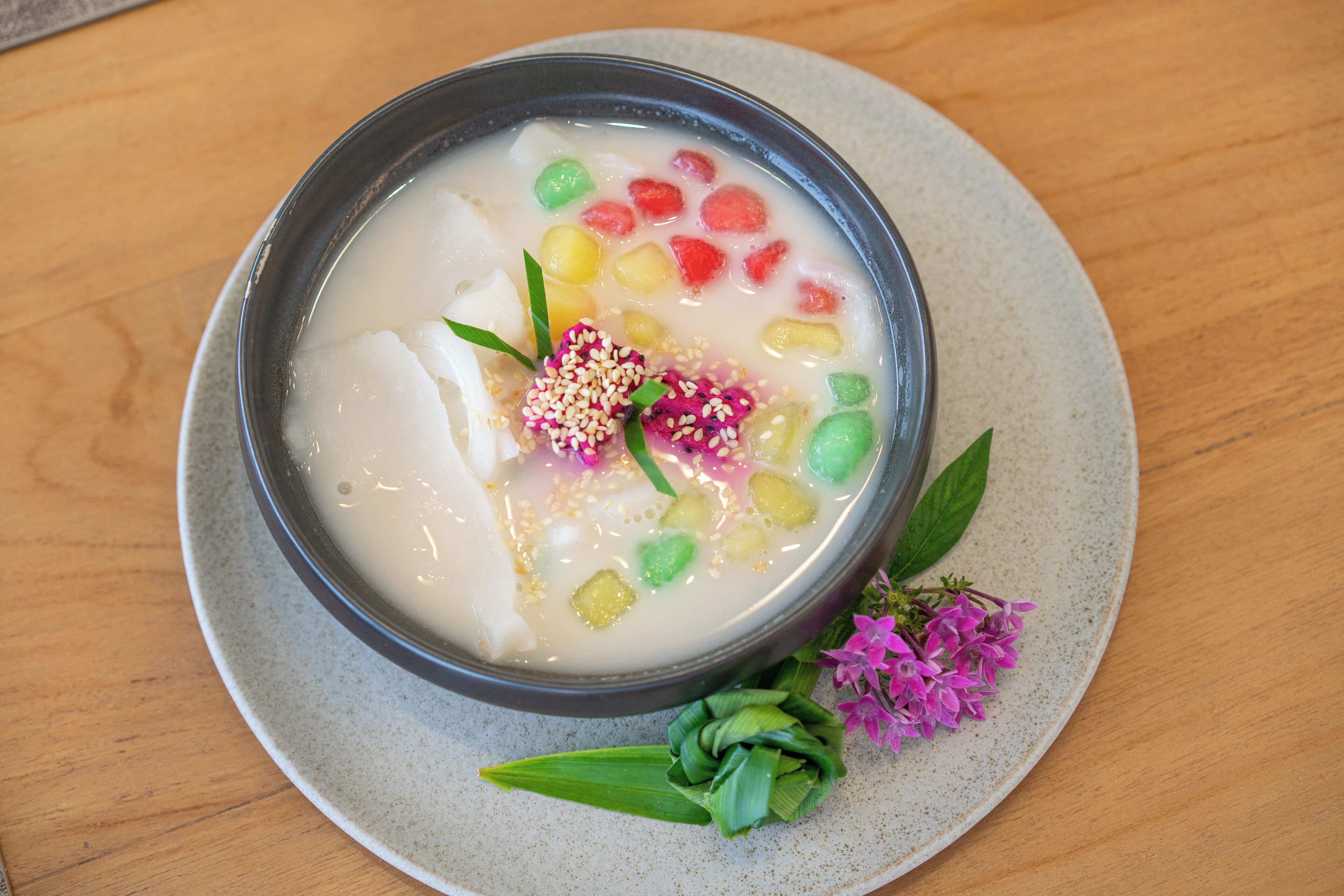 A bowl of dessert with various colorful ingredients on a plate.