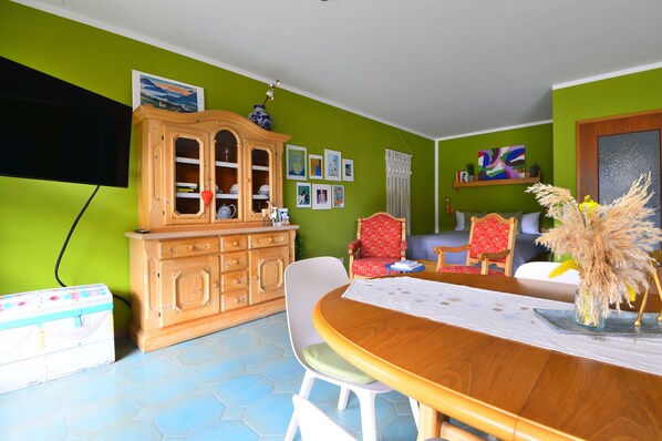 A dining area with a wooden table, chairs, a cabinet, and a television mounted on the wall. - bright apartment with a large balcony in the very center of the town. (Garmisch-Partenkirchen)