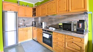 Eine Küche mit Holzausstattung, einem Edelstahlkühlschrank, einer Mikrowelle und einem eingebauten Backofen.