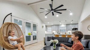 Una sala de estar moderna con un sillón colgante, un sofá y un comedor.