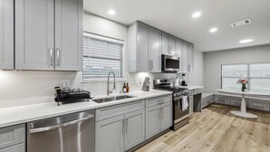 Una cocina moderna con gabinetes grises, electrodomésticos de acero inoxidable y una isla central.
