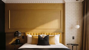 Habitación de hotel con una cama grande, una mesa redonda, una lámpara y una lámpara de pared.