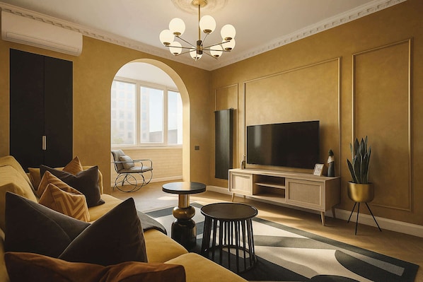 A living room with a sofa, TV, arched window, and a chandelier.
