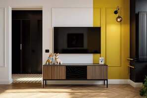A modern living room with a large flat-screen TV mounted on a white wall, a wooden console table with decorative items, and a yellow accent wall.