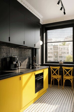 A modern kitchen with black cabinets, a yellow countertop, and a window with a view of buildings.