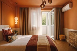 A hotel room with a bed, a bedside table with a lamp, a dresser, and a view of the outdoors.
