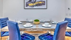 Un coin repas avec une table en bois dressée pour six personnes, entourée de chaises à l’assise bleue.