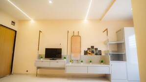 A modern living room with a flat-screen TV, a large mirror, and a minimalist shelving unit.