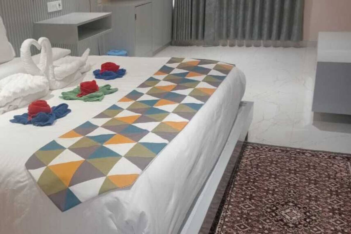 A hotel room with a large bed, a desk, and a chair.