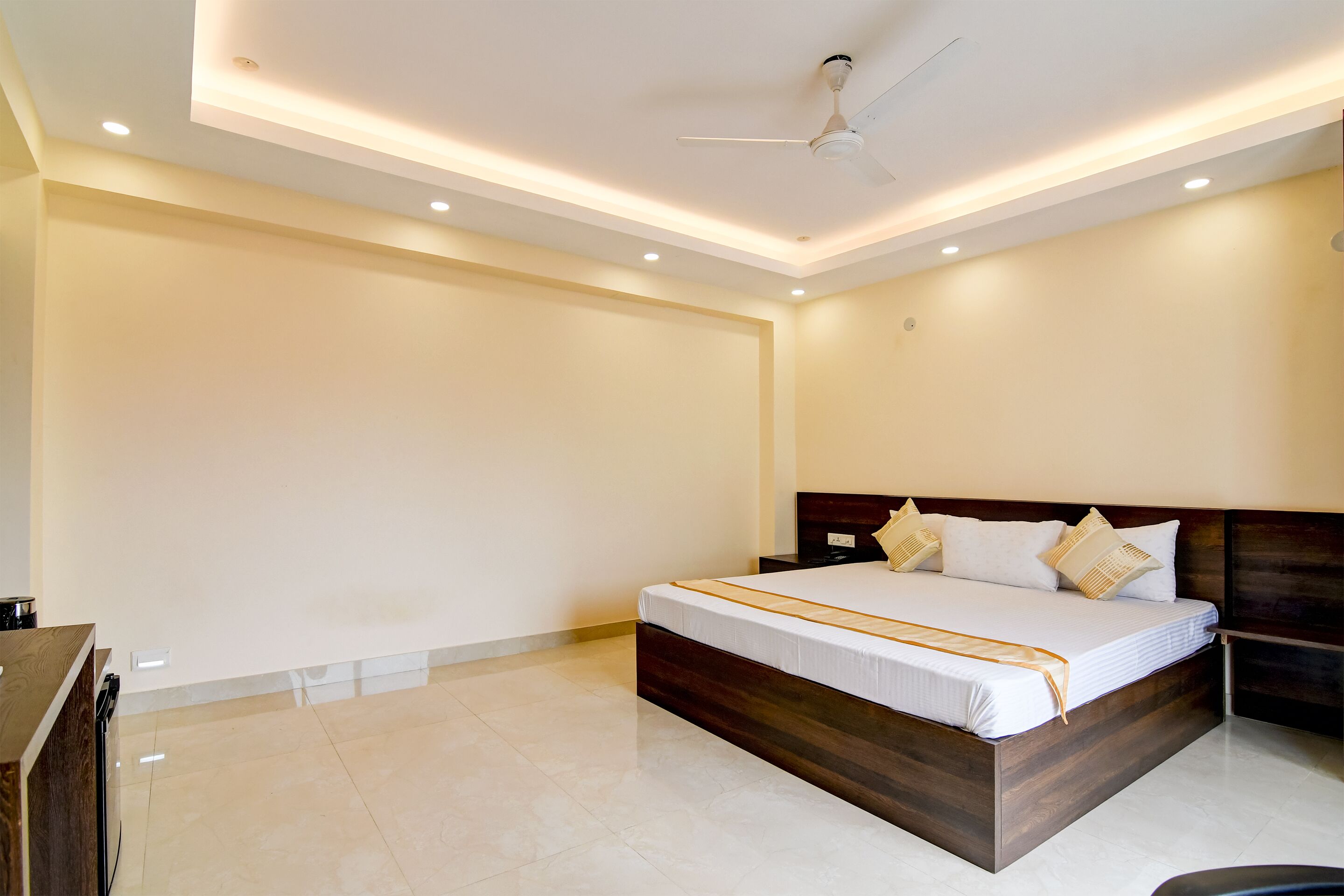 A spacious bedroom with a large bed, a ceiling fan, recessed lighting, and a wooden headboard.