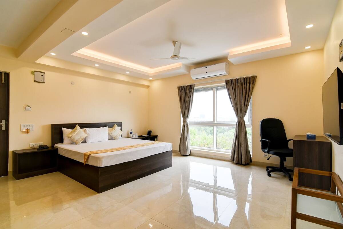 A modern hotel room with a large bed, a desk, and a chair.