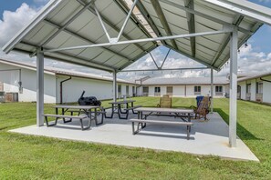 A covered outdoor area with picnic tables and a barbecue grill.