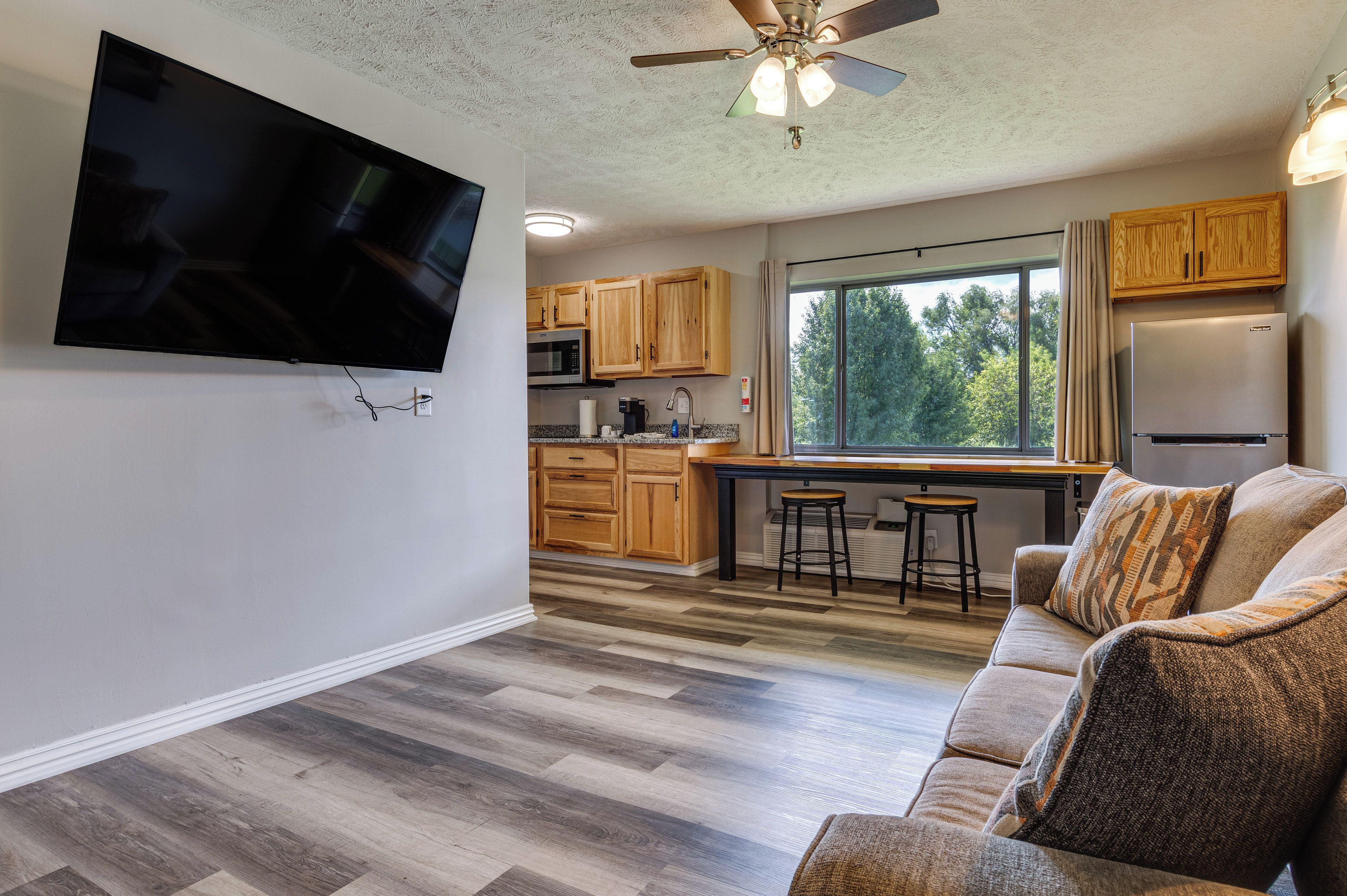 A modern kitchen with wooden cabinets, a built-in microwave, and a large window.
