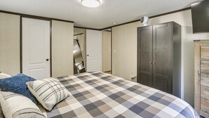 Une chambre à coucher avec une couvre-lit à carreaux, une armoire et un luminaire au plafond.