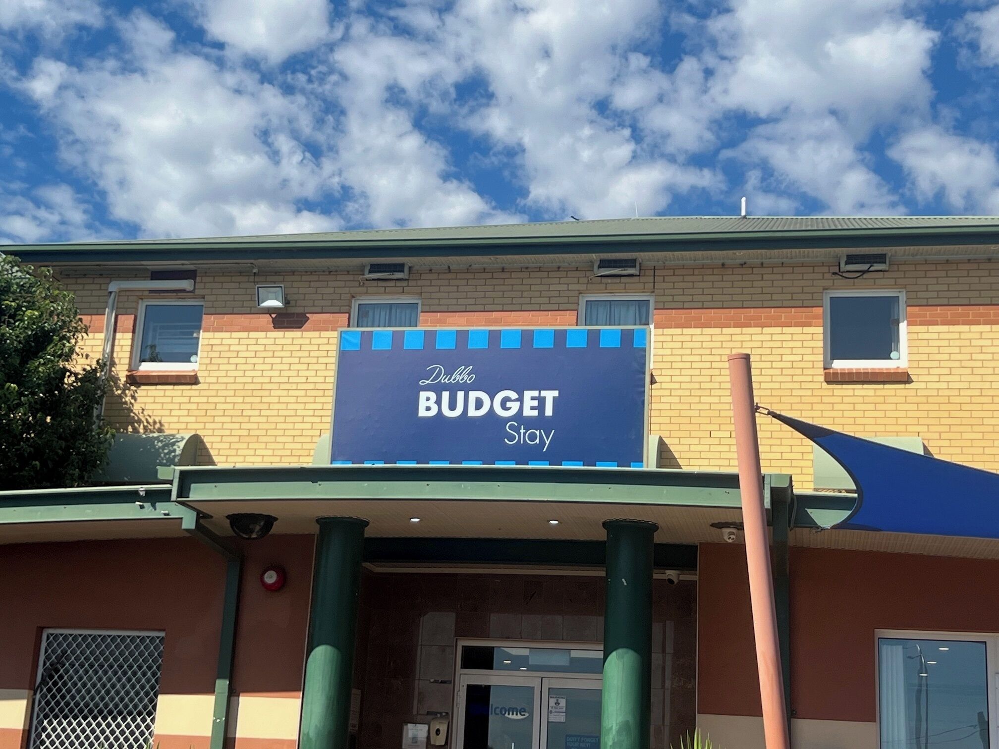 A building with a sign that reads "Dubbo BUDGET Stay".