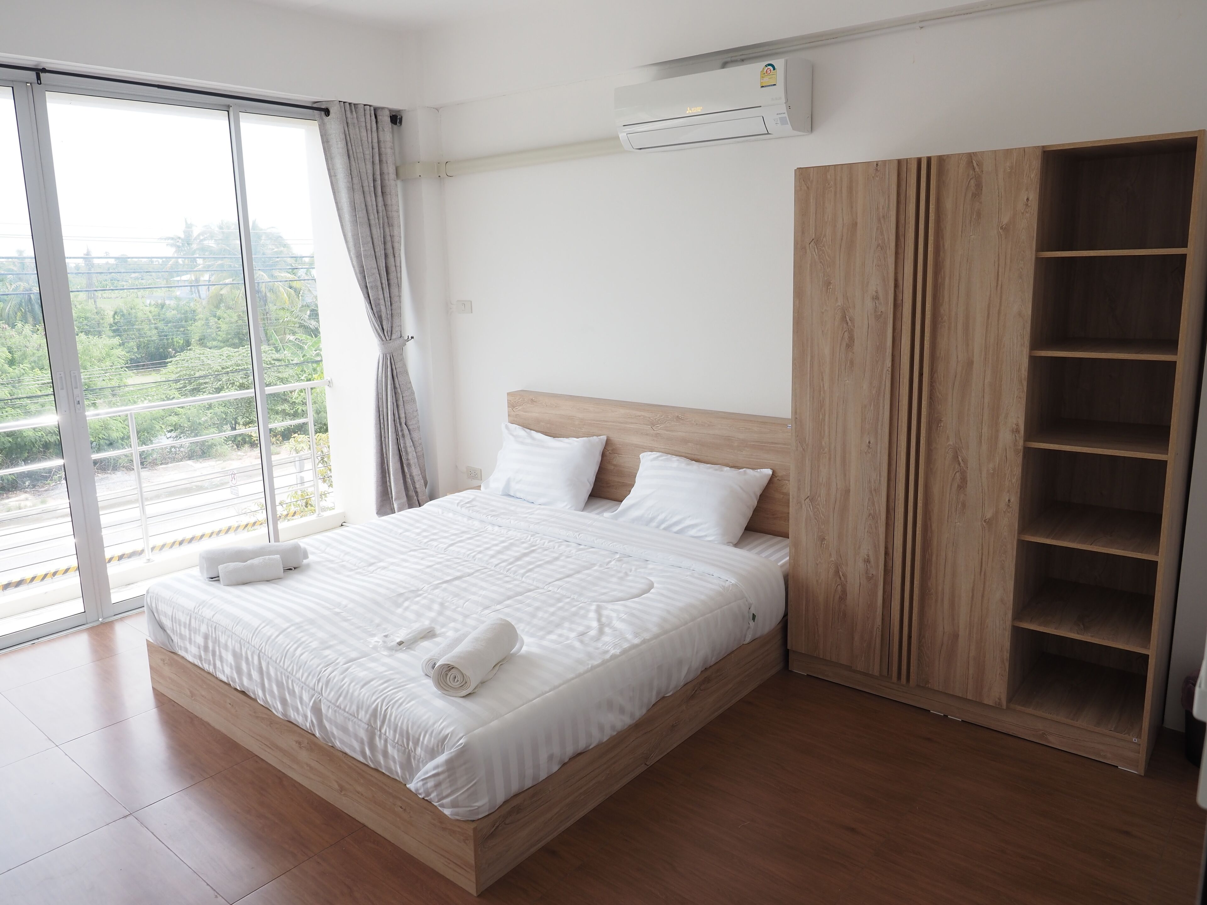 Quarto com uma cama grande, um guarda-roupa de madeira e uma janela com cortinas.