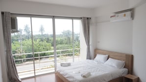 Ein Schlafzimmer mit einem großen Bett, einem Holzkopfstück, einem Nachttisch und einem Fenster mit Vorhängen.