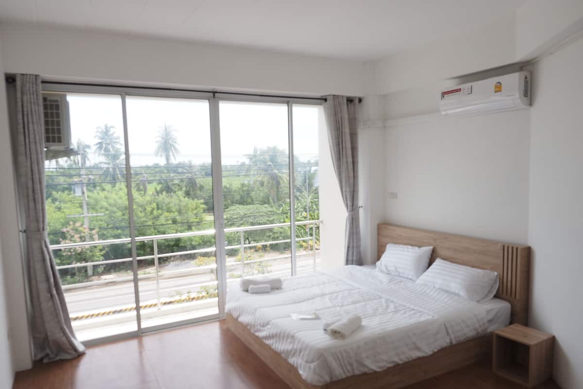 Un dormitorio con una cama grande, un cabecero de madera, una mesita de noche y una ventana con cortinas.