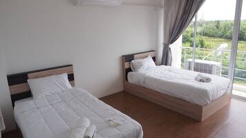 A hotel room with two beds, a large window with a view of greenery, and an air conditioning unit on the wall.