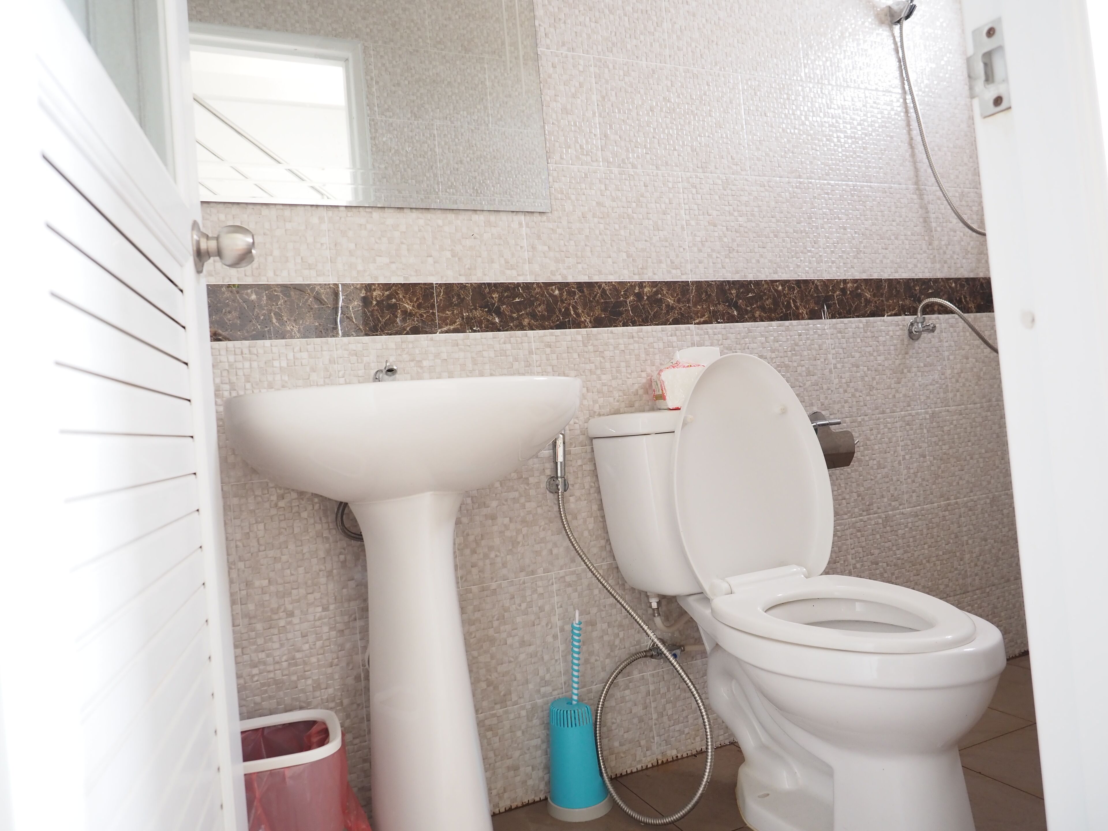 A bathroom with a white sink, toilet, and shower.