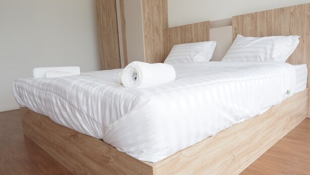 Ein Bett aus Holz mit weißer Bettwäsche und Kissen.