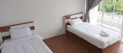 Una habitación de hotel con dos camas, un ventanal con vistas y un equipo de aire acondicionado.
