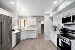 A modern kitchen with white cabinetry, stainless steel appliances, and a central island.