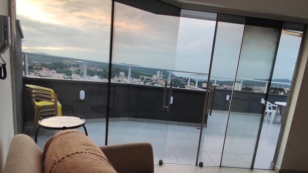 Een balkon met een bank en stoelen, met uitzicht op een stadsbeeld en een wateroppervlak.