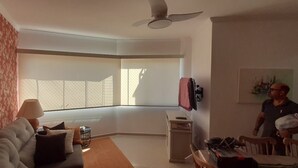 Een woonkamer met een bank, een salontafel, een lamp, een televisie en een plafondventilator.