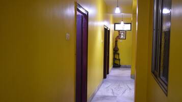 Un passadís amb parets grogues i un sòl de marbre que condueix a una porta al final.
