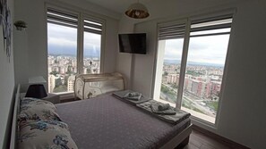 Enjoy a city view from the comfort of a spacious bed, paired with a flat-screen TV and a convenient bedside table.