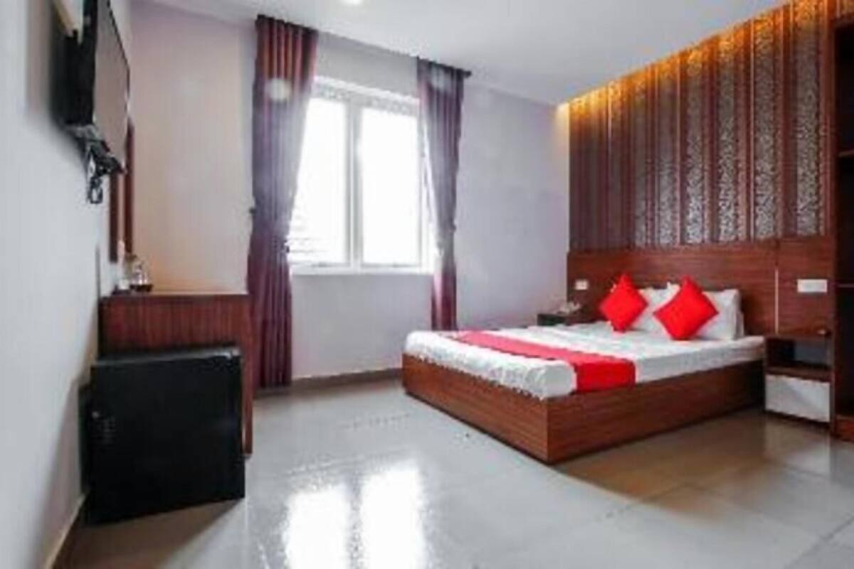 A hotel room with a large bed, a wardrobe, a desk, and a window with curtains.